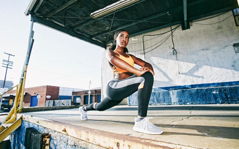 Mixed Race woman stretching legs on loading dock