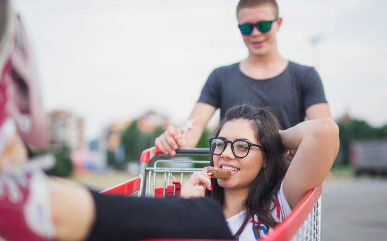 19 years old couple enjoy outdoors. They are having fun at the shopping centre with trolley