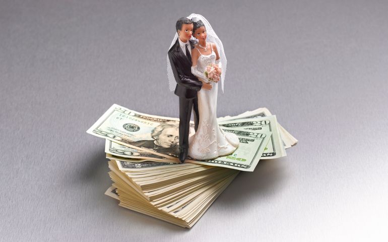 Wedding couple figurine standing on a pile of Dollars