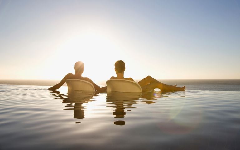 Friends soaking in infinity pool near ocean