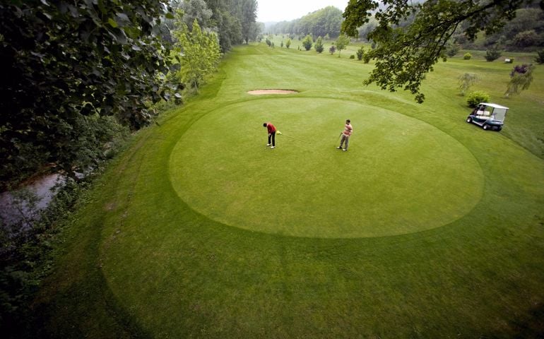 France, Dordogne, two golfers on green at golf course, elevated view