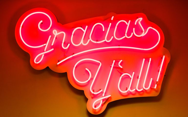 Gracias Y'all closeup of orange red neon sign in store shop for business on window