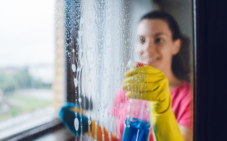 Young woman wiping windows at home