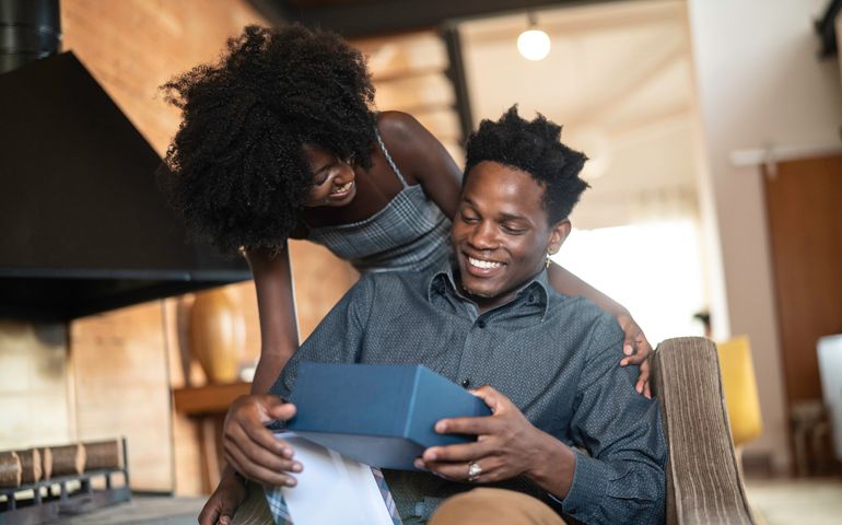 African descent brazilian couple exchanging gifts at home.