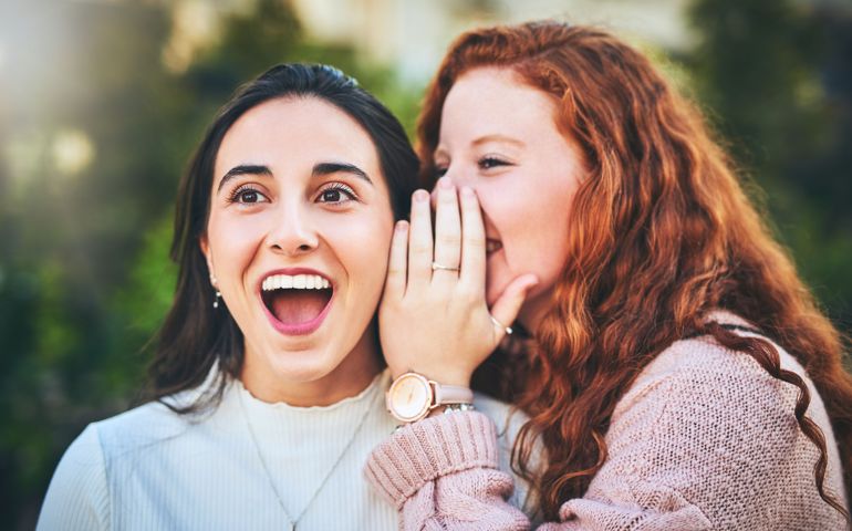 Shot of a woman whispering something into her friend's ear