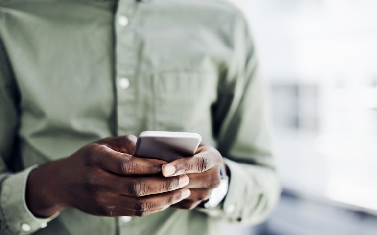 Closeup shot of an unrecognisable businessman using a cellphone in an office