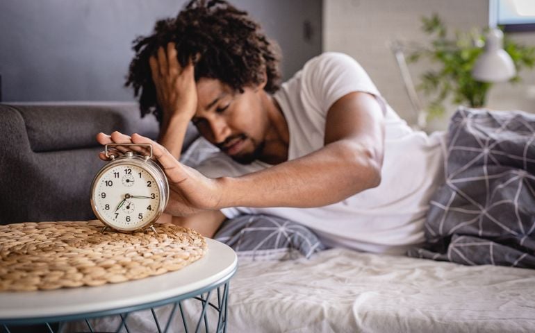 A man wakes up in bed under stress