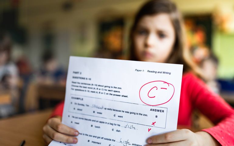 Close up of a schoolgirl showing her C- grade on a test at elementary school.