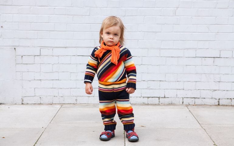 A small boy posing in front of brick wall