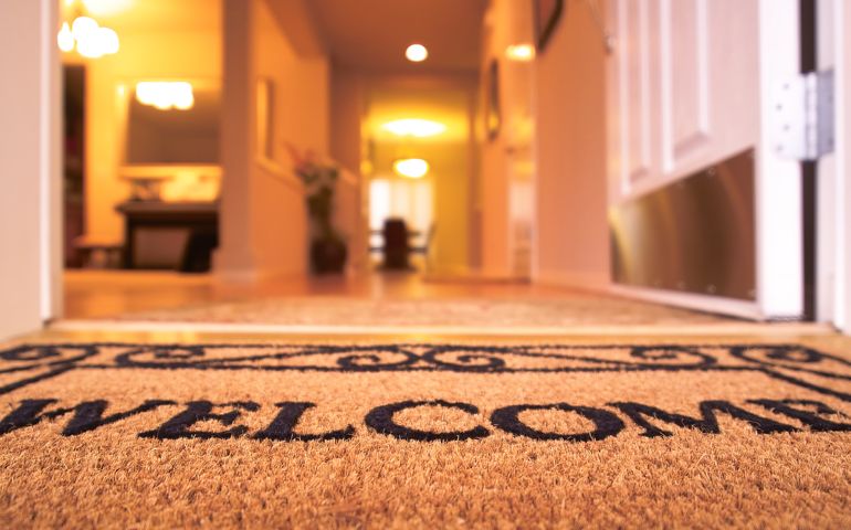 Photo of a welcome mat, looking beyond the threshold of a home.