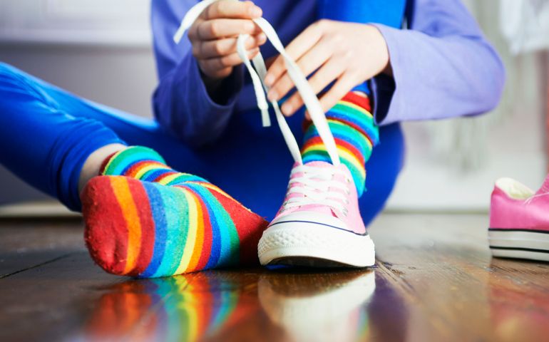 young child tying shoe laces with colourful socks