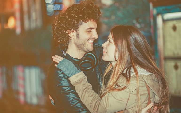 Young couple standing embraced on the street at night