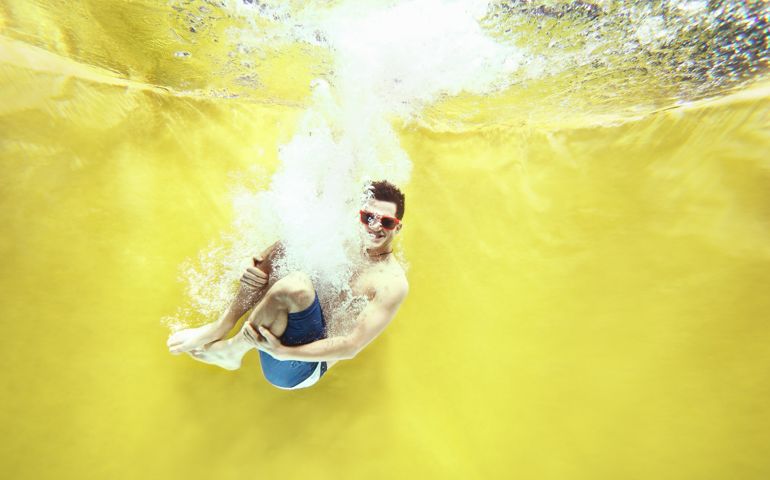 Boy jumping into water on yellow background