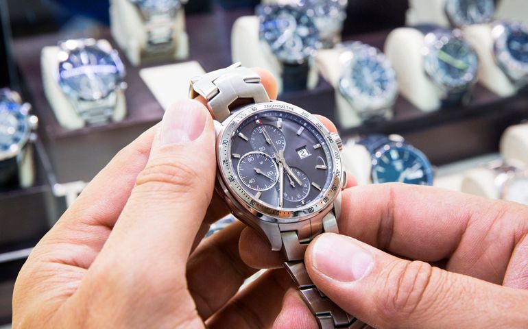 Mens wristwatch being held in a watch shop.