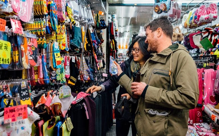 Caucasian male and Asian female in accessories store having fun with socks
