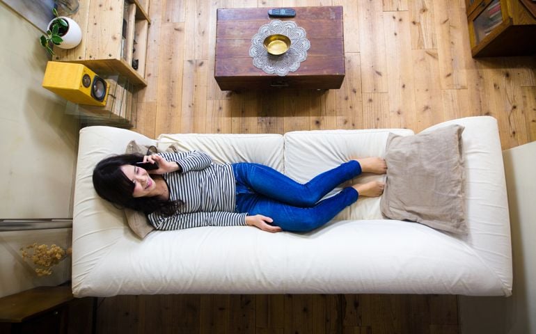 Aerial view of a young adult female lying on the sofa talking on the phone. Kyoto, Japan. December 2016