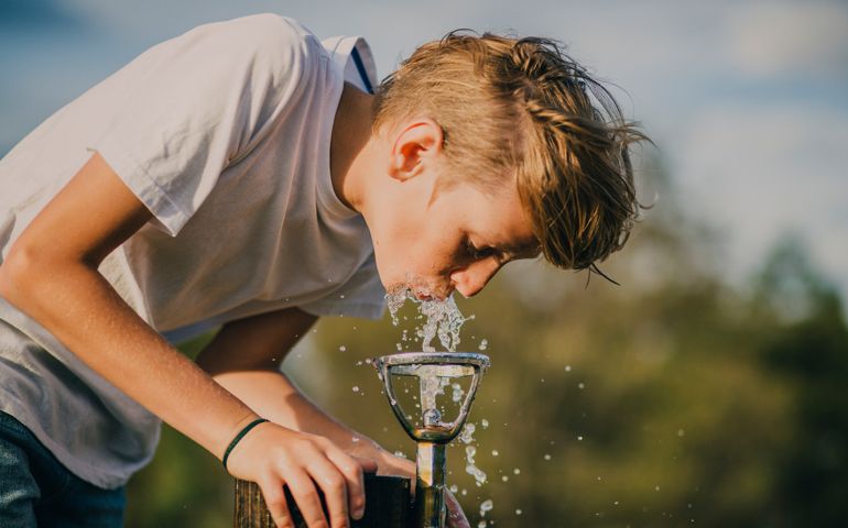 Young boy drinking from a water fountain in a park in Melbourne, Australia.