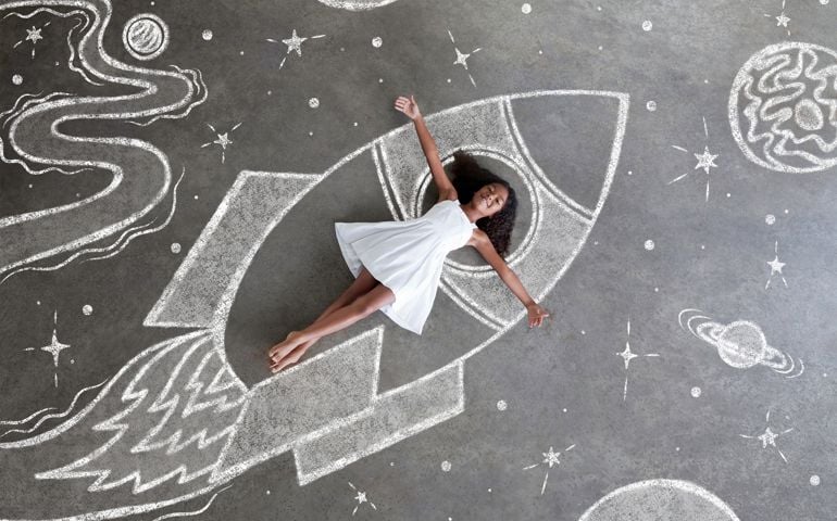 Barefoot girl in white dress explores a whimsical chalkboard universe inside her chalkboard spaceship, arms wide open