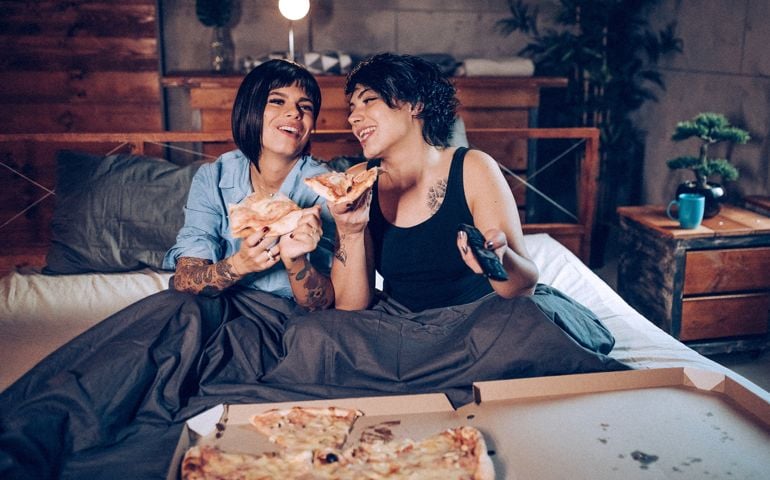 Lesbian couple watching tv in bed