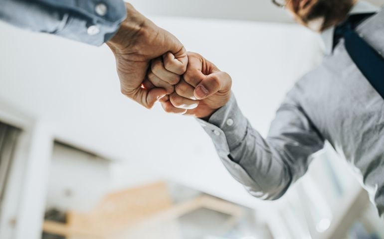 Close up of two unrecognizable businessmen greeting each other with fist bump.