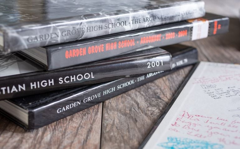 A view of several high school yearbooks, on a wooden surface.