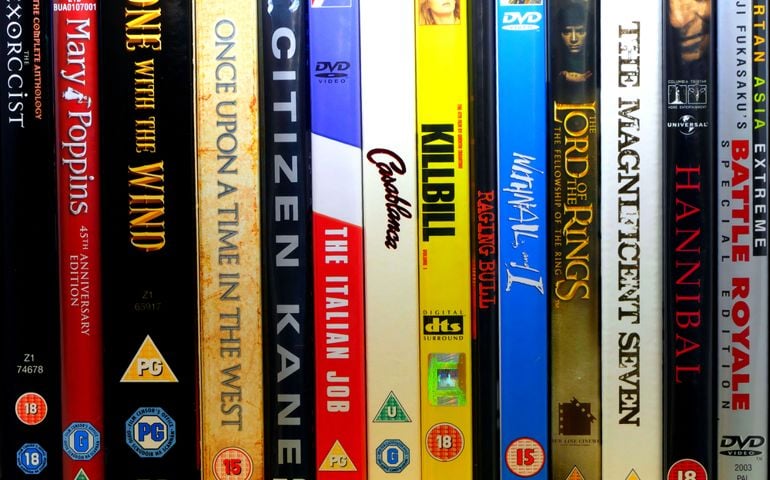 A random selection of lined-up DVD discs of classic movies from various film genres.