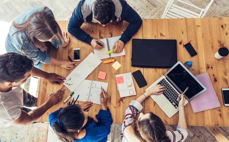 overhead view on young business people around wooden desk