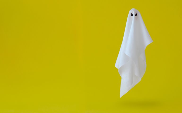 White ghost sheet costume flying in the air with yellow background. Minimal Halloween scary concept.