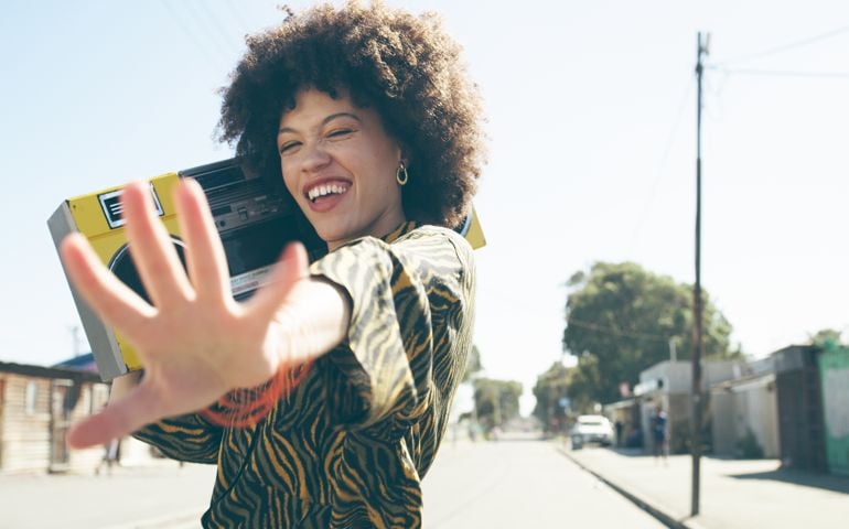 Shot of an attractive young woman listening to music on a boombox in an urban setting