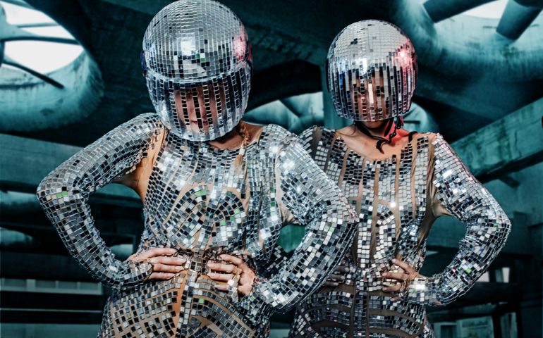 Two Race Car Driving Females in shiny suits in post-apocalyptic settings