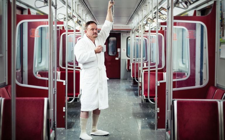 Early commuter wearing bathrobe and slippers on the underground train.