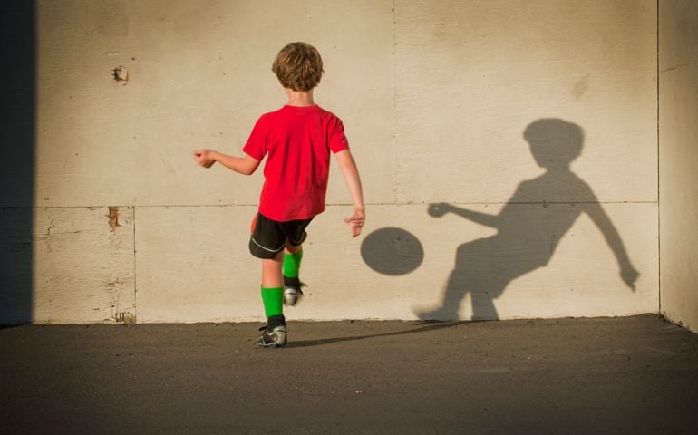 young boy playing "wall ball" with his shadow