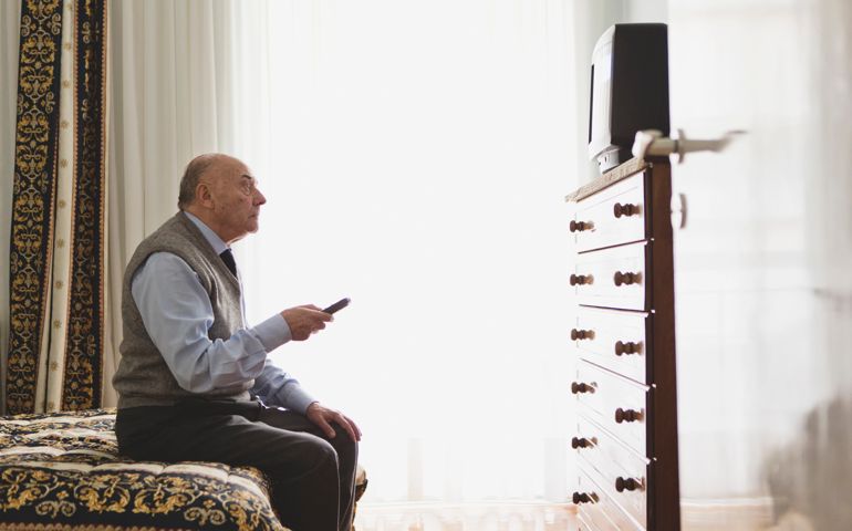 Portrait of a senior man watching television