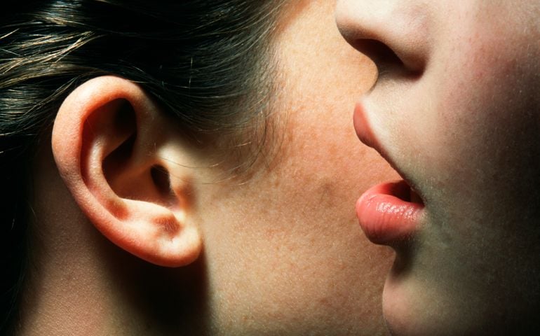 Young Woman Whispering to Another Woman