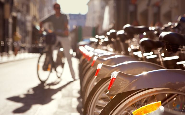 Man standing next to row of city rental bikes