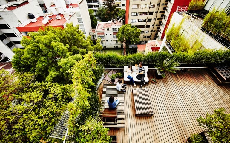 Family sitting together on rooftop garden patio of home with city in background
