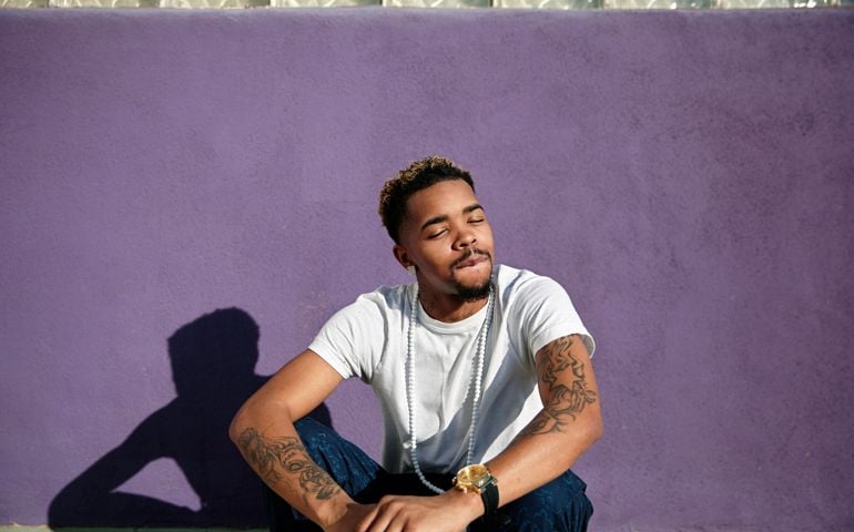 Hip young man sitting against colorful wall.