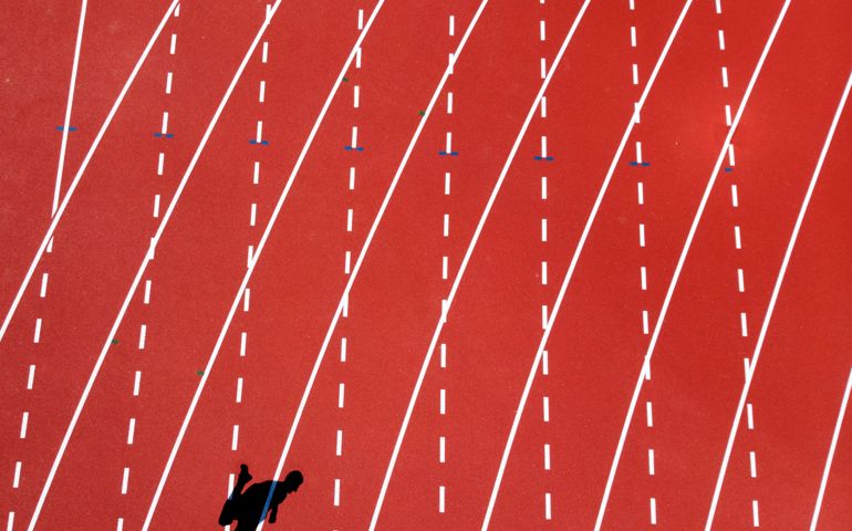 A shadow of a young man running on track lanes seen from drone in Vancouver.