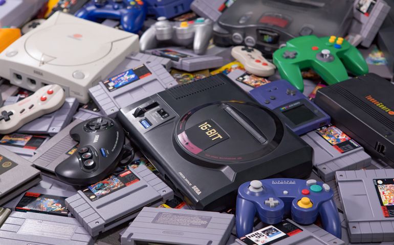 Many different types of video game systems, controllers, and games shot in a studio.