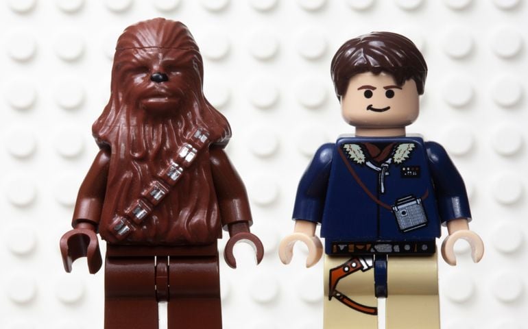 Lego style mini figure of Han Solo and the Wookiee sidekick Chewbacca against a white Lego board