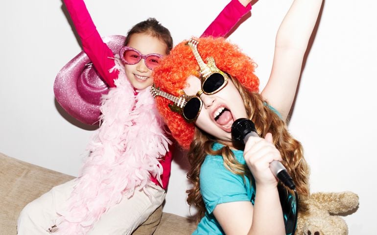 Girls singing into microphones at party