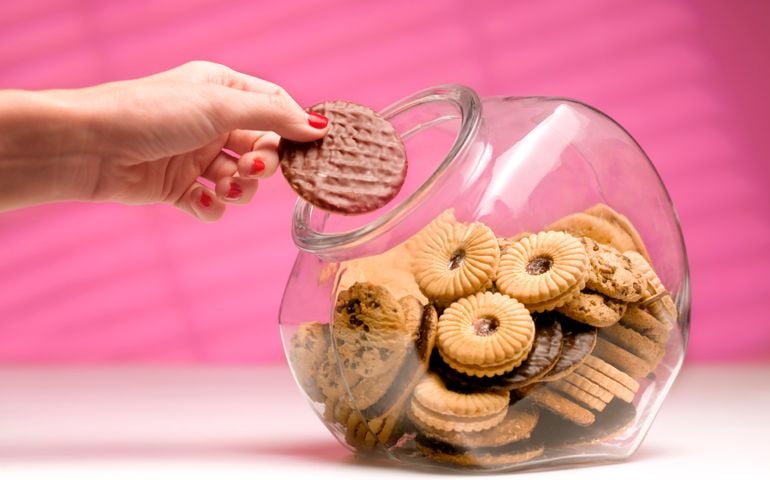 dieting woman sneaking a biscuit treat from the cookie jar