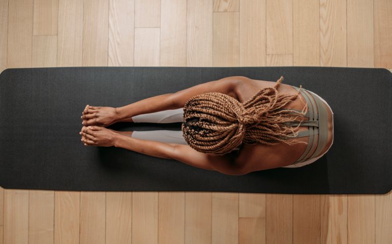 Overhead photo of sportswoman doing stretching exercise on fitness mat.