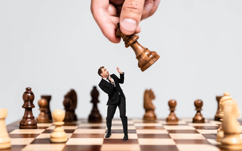 cropped view of man playing chess and frightened marionette looking at figure isolated on grey