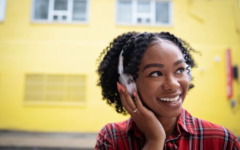 Young African ethnicity female listening to music via wireless headphones