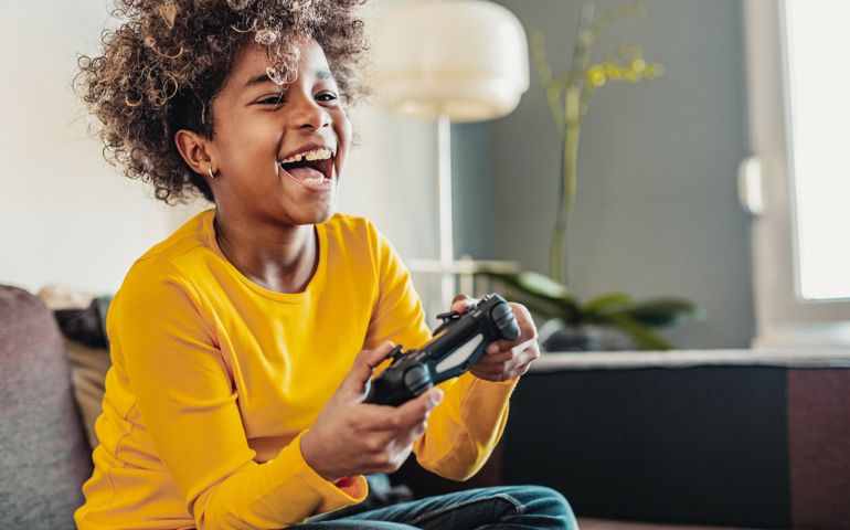 Young African American little girl at home with playing video games