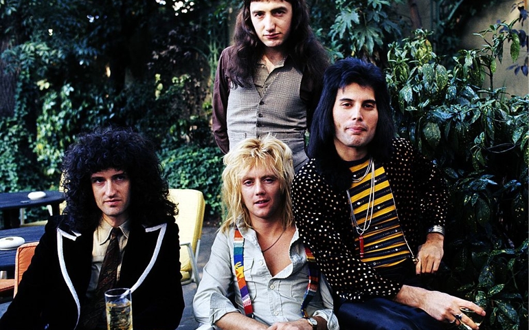 Brian May, John Deacon (standing), Roger Taylor and Freddie Mercury of British rock group Queen at Les Ambassadeurs where they were presented with silver, gold and platinum discs for sales in excess of one million of their hit single 'Bohemian Rhapsody', which was No 1 for 9 weeks on September 8, 1976 in London, England.