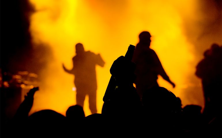 concert crowd rising a bottle. silhouetes of rappers on stage