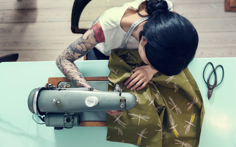 Overhead view of a female dressmaker working on a sewing machine in her design studio.