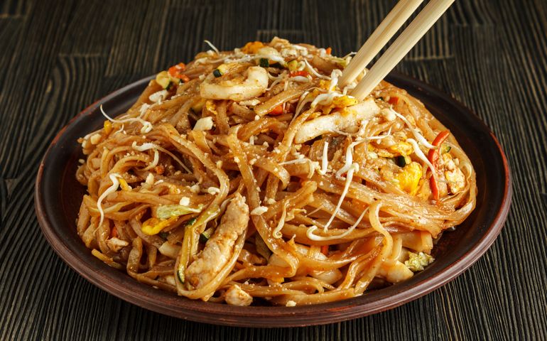 Pad thai with chopsticks on wood close-up